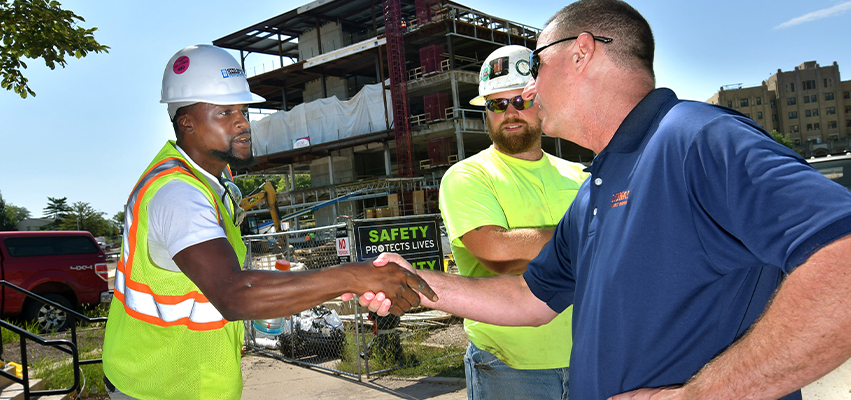 Working shaking hands at a construction site.