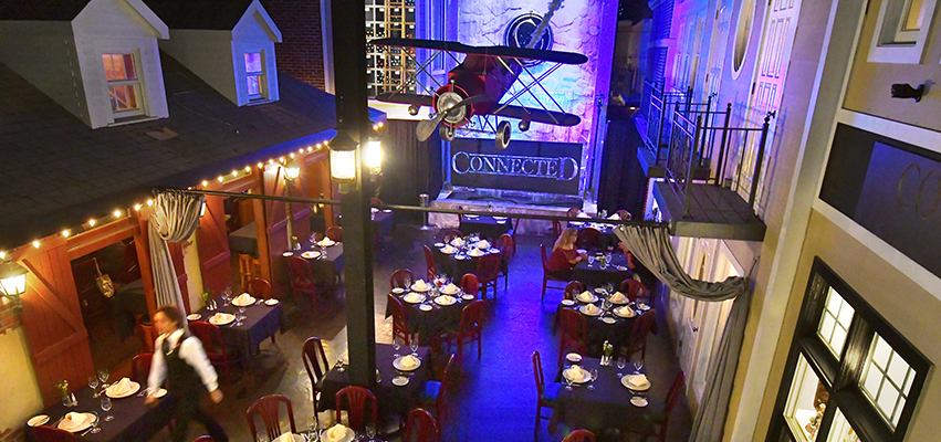 Shot from above the dinning room of "Connected" with store front facades and an air plane hanging from the ceiling