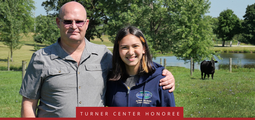 Turner Center Nominee: a father and daughter embracing with a field and cow in the background