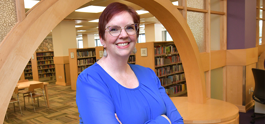 Woman Standing in front of a wooden archway in the Peoria Public Library