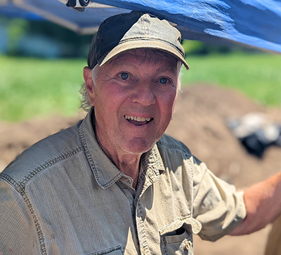 A man wearing a tan shirt and baseball cap