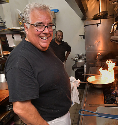 Troy Ummel in kitchen with flaming skillet on the kitchen range