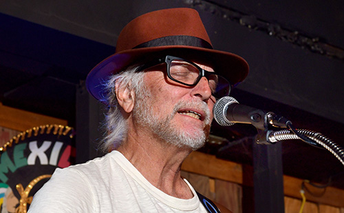 Man in hat singing into a microphone