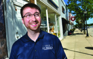 Man standing on sidewalk in front of downtown businesses