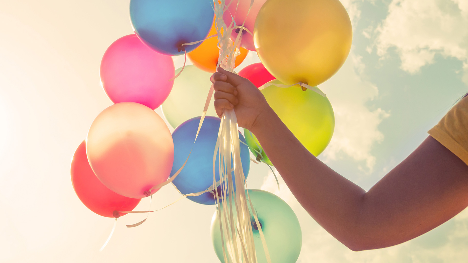 hand holding multi-color balloons