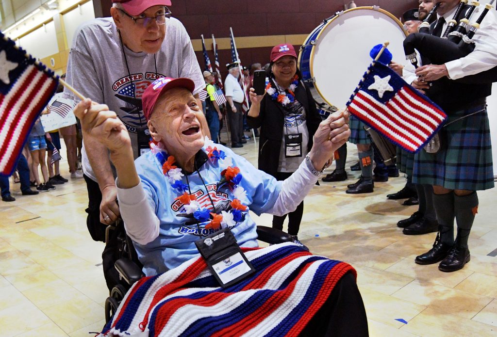 WWII veteran Alvah Purvis , 99, waves his flags as he is greeted by the applauding crowd after returning to the Gen. Wayne A. Downing Peoria International Airport with guardian Greg Krucek