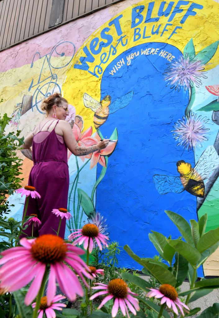 Jessica McGhee works on one of her murals on a wall of One World Café