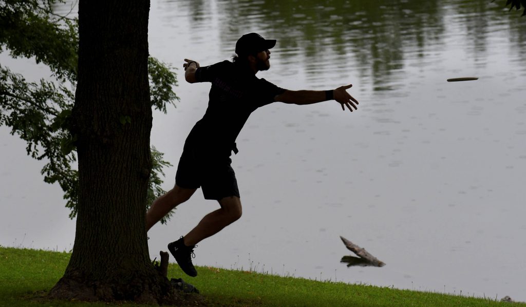 A competitor throws a disc to the target along Lake Eureka during the 2023 Ledgestone Open